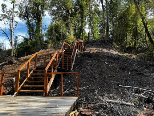 a set of wooden stairs on a hill with trees at Domo Panigal in Hornopiren