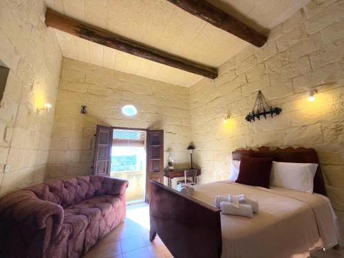 a bedroom with a bed and a couch in a room at Traditional House of Character in Gharb Gozo in Għarb