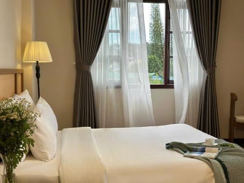 a bedroom with a bed and a window at Túi Ba Gang Boutique Hotel in Da Lat