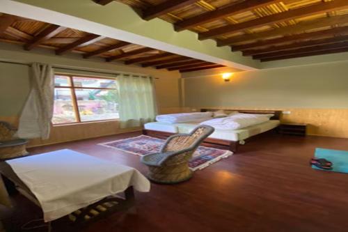 a room with two beds and a chair and a window at Namkha Homestay by StayApart in Tabo