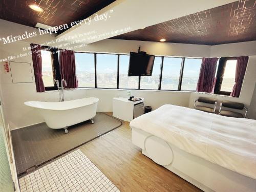 a bedroom with a tub and a bed and a television at 幸福星空時尚旅館 in Luodong