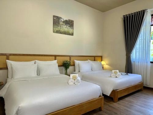 two beds in a hotel room with white sheets at Túi Ba Gang Boutique Hotel in Da Lat