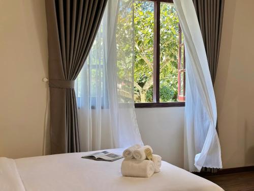 a pair of towels sitting on a bed in front of a window at Túi Ba Gang Boutique Hotel in Da Lat