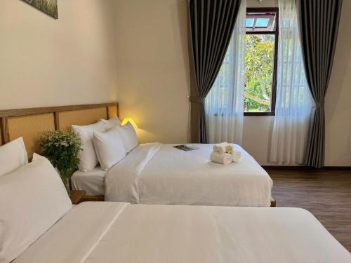 two beds in a hotel room with white sheets at Túi Ba Gang Boutique Hotel in Da Lat