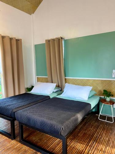 two beds in a room with blue and green walls at 11th Earth Farm and Resort in Nabua