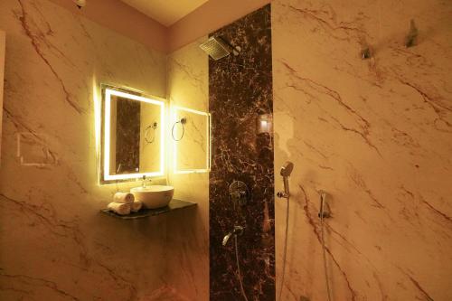a bathroom with a sink and a shower with a mirror at Hotel RJ in Patna