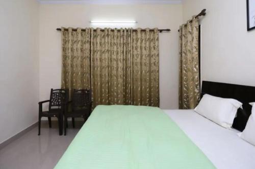a bedroom with a bed and a chair and curtains at Pulu Lodge & Dining by StayApart in Jorhāt