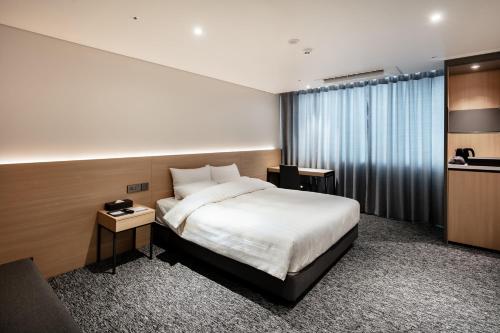 a hotel room with a bed and a large window at Icheon Skysun Hotel in Icheon