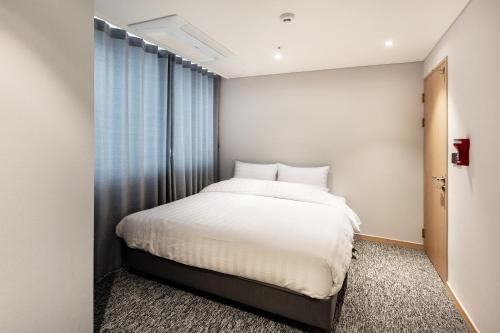 a bedroom with a white bed and a window at Icheon Skysun Hotel in Icheon