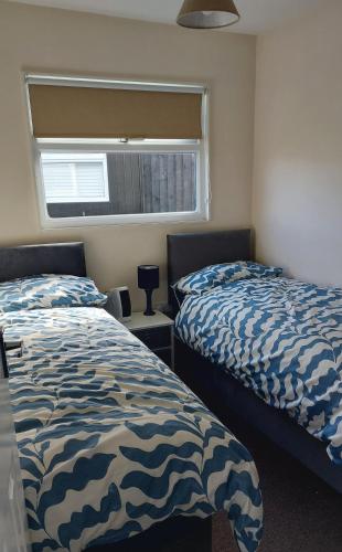 a bedroom with two beds and a window at Grand Chalet 64 Disabled Friendly in Skegness