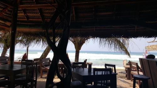 a restaurant on the beach with tables and chairs at The Den Guest House in Hikkaduwa