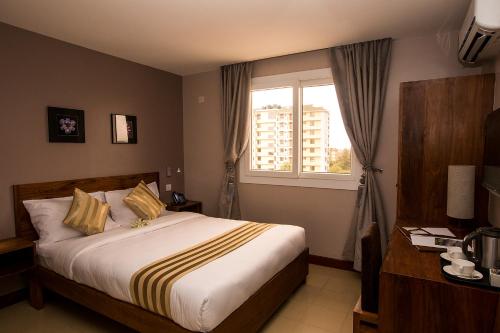 Habitación de hotel con cama y ventana en Venus Premier Hotel en Arusha