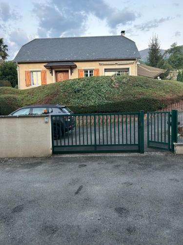 une voiture garée derrière une porte verte devant une maison dans l'établissement Artalens, à Artalens-Souin