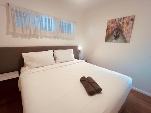 a bed with a pair of shoes sitting on top of it at Cosy Homes - 15 Minutes Away From Melbourne Airport in St Albans