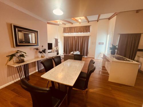 a living room with a table and chairs and a kitchen at Cosy Homes - 15 Minutes Away From Melbourne Airport in St Albans