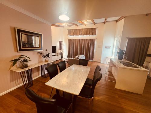 a living room with a table and chairs and a kitchen at Cosy Homes - 15 Minutes Away From Melbourne Airport in St Albans