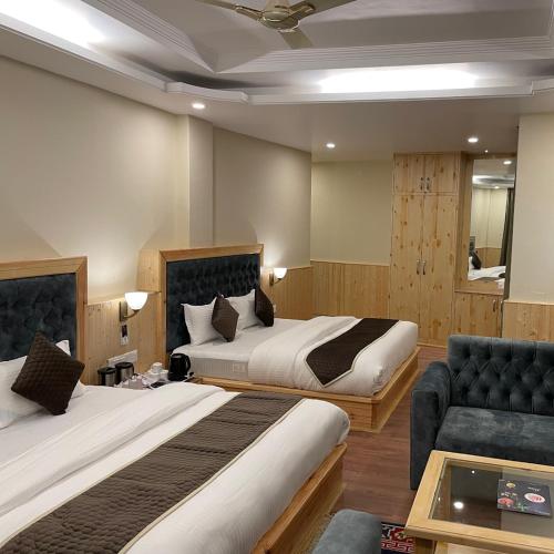 a hotel room with two beds and a couch at HUKAM'S HOLIDAY HOME by HHH in Kasol