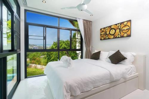 Un dormitorio con una cama blanca y una ventana grande. en Namara The Residences B, en Kamala Beach