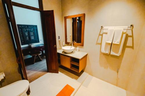 a bathroom with a sink and a toilet and a mirror at Sri Aksata Ubud Resort in Ubud
