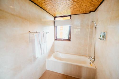 a bathroom with a bath tub and a window at Sri Aksata Ubud Resort in Ubud