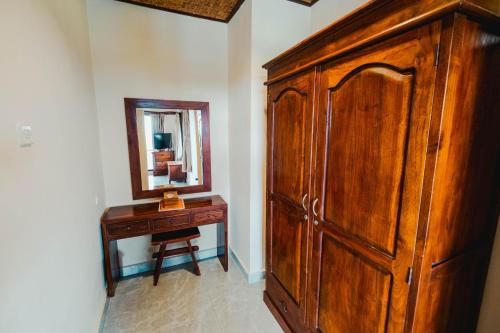 a wooden cabinet and a mirror in a room at Sri Aksata Ubud Resort in Ubud