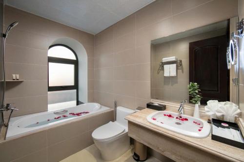 a bathroom with a tub and a toilet and a sink at Halios Hotel Halong in Ha Long