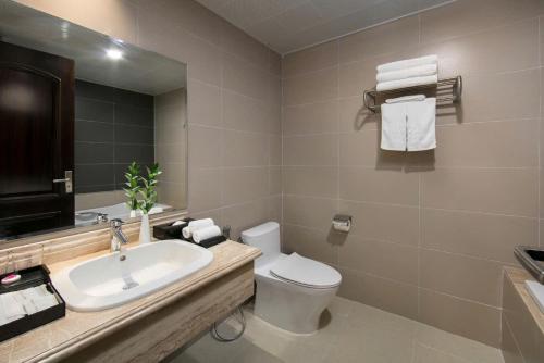 a bathroom with a sink and a toilet and a mirror at Halios Hotel Halong in Ha Long