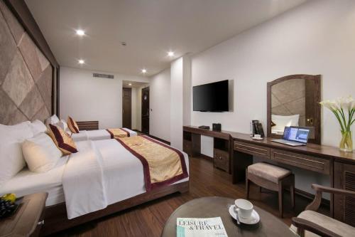 a hotel room with a bed and a desk with a computer at Halios Hotel Halong in Ha Long