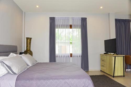 a bedroom with a bed and a window and a television at 2 Bedroom Villa with Pool & Close to Setangi Beach in Mangsit
