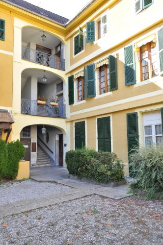 a yellow building with green shutters and a balcony at Appartements CONFIDENCE hyper centre calme - SEJOURAIXLESBAINS in Aix-les-Bains