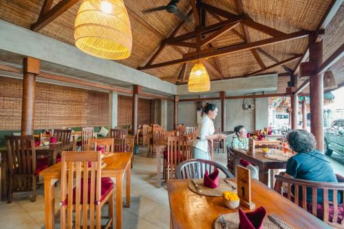 a woman standing in a restaurant with people sitting at tables at Sri Aksata Ubud Resort in Ubud