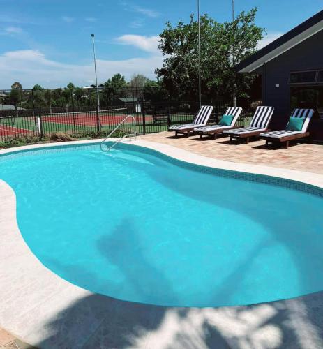 a large blue swimming pool with two lounge chairs at Hunter Oasis in Morpeth