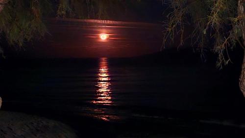 a full moon over the water at night at Ancient Thera Apartments in Kamari