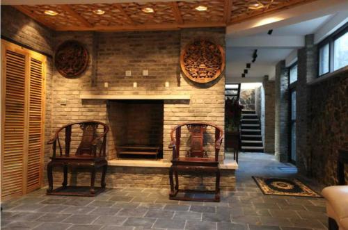a stone fireplace in a living room with two chairs at Home of the Great Wall in Huairou