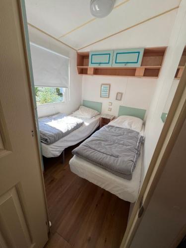 une petite chambre avec deux lits et une fenêtre dans l'établissement La Pinède Ensoleillée au Camping La Dune Blanche, à Camiers