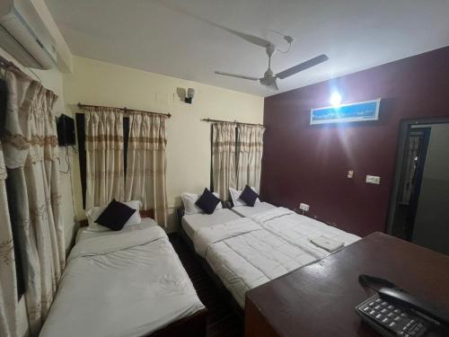 a room with two beds and a desk with a keyboard at Hotel Blue lake in Pokhara