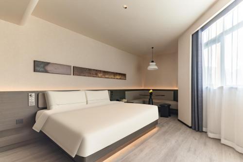 a bedroom with a white bed and a large window at Atour Hotel Shanghai Hongqiao Shuicheng Road in Shanghai