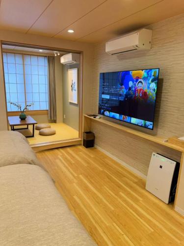 a bedroom with a large flat screen tv on the wall at M house asakusa kaminarimon tokyo in Tokyo