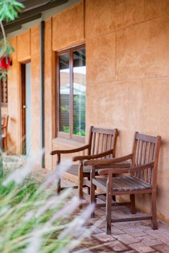 two wooden benches sitting on the side of a building at Mud Hut Motel in Coober Pedy