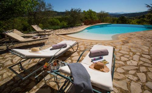 a swimming pool with two lounge chairs and a table at Le Jas de Péguier in Châteauneuf-Val-Saint-Donat