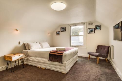 1 dormitorio con cama, ventana y silla en Brampton Cottage en Hobart