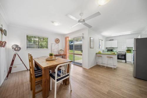 a kitchen and dining room with a table and a refrigerator at Tides & Tails Abode - Coolum Beach Pet Friendly Home in Coolum Beach