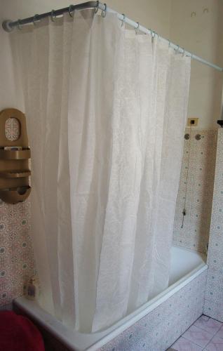 a white shower curtain on a tub in a bathroom at B&B Early Leaving Bergamo Airport in Bergamo