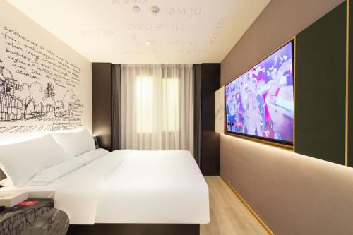 天津市にあるCitiGO Hotel Tianjin Binjiang Roadの大きな白いベッドとテレビのある寝室