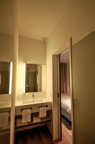 a bathroom with a sink and mirror and a bed at Cadix 35 in Antwerp