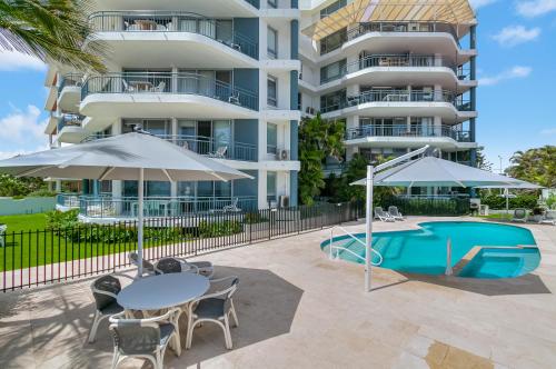 Cet appartement dispose d'une piscine, de tables et de parasols. dans l'établissement Oceanside Resort - Absolute Beachfront Apartments, à Gold Coast