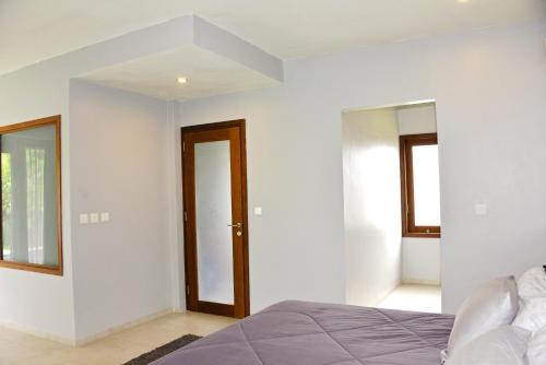 a white bedroom with a bed and a mirror at 2 Bedroom Villa with Pool & Close to Setangi Beach in Mangsit
