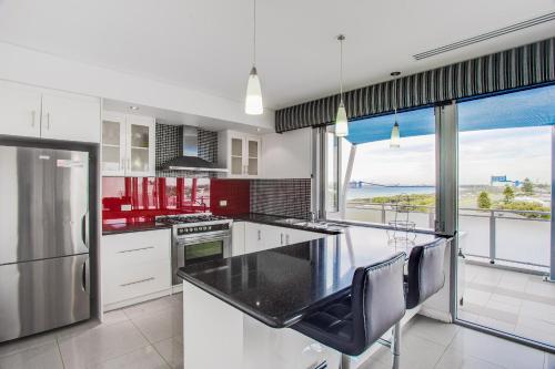 a kitchen with white cabinets and a view of the ocean at Spinnakers by Rockingham Apartments in Rockingham
