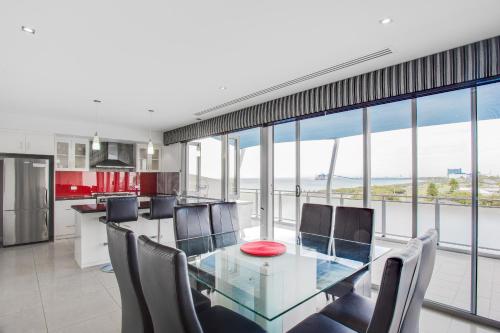 a dining room with a glass table and chairs at Spinnakers by Rockingham Apartments in Rockingham