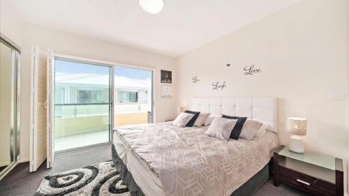une chambre avec un grand lit et une grande fenêtre dans l'établissement Pacific Blue Apartment 258, 265 Sandy Point Road, à Salamander Bay